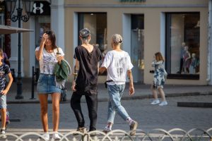 Фотография двух мужчин с татуировками на руках, идущих по улице города. Видны татуировки в различных стилях.