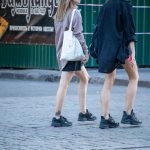 Фотография двух девушек, идущих по улице, с минималистичными татуировками на лодыжках. Небольшие тату в стиле минимализм.