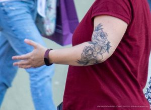 Фото тату: крупный рисунок пионов в черно-серых тонах на плече девушки. Детализированная проработка лепестков, реалистичный стиль, женственный дизайн.