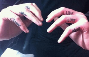 Фотография татуировок на пальцах рук. Надписи 'Live', 'Love', 'Asap' и 'The New Classic', выполненные черными чернилами, выглядят стильно и современно.