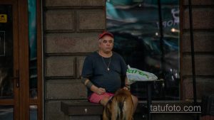 Фото мужчины в кепке и с татуировкой на руке. Черно-белый рисунок татуировки в стиле реализм.