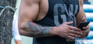 Фото тату: крупный план татуировки на руке мужчины. Видны темные контуры и детализированный рисунок, возможно, растительный орнамент.