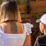 Фотография крупным планом татуировки розы и черепа на спине девушки. Детализированный рисунок в стиле blackwork с геометрическими элементами. Высокая контрастность и четкость линий.