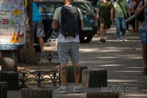 Фото татуировок на руках мужчины с рюкзаком. Видны рукава с татуировками, повседневная одежда, городская обстановка.