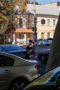 Фото тату на руке мотоциклиста в Одессе. Видны рукава с татуировками, едет по улице, городская среда.