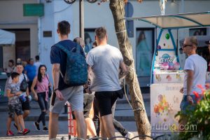 Фотография мужчины с татуировкой на руке, идущего по улице города. Видна часть татуировки в виде геометрических узоров и абстрактных фигур.