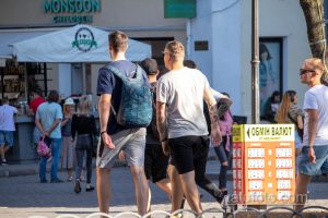 Фото мужчины с татуировкой на руке, идущего по улице города. Видна часть татуировки в стиле традиционной японской татуировки.