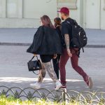 Фотография двух женщин, идущих по улице, с заметными татуировками на ногах. Различные стили и рисунки демонстрируют их индивидуальность.