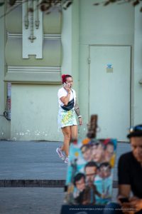 Фото тату на руке девушки, говорящей по телефону на улице. Видны детали рисунка татуировки и ее стиль.