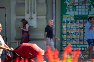 Фото тату на руке мужчины, стоящего на улице. Видны детализированные рисунки на предплечье, сочетающие темные и светлые оттенки.