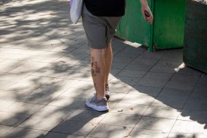 Фото тату на икре с изображением мультяшных зверюшек: жирафа и динозавра. Яркие цвета и простой стиль.