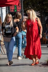 Фотография двух женщин на улице, одна из которых в красном платье, демонстрирует татуировку тигра на руке.