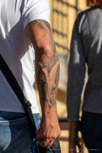 Фотография татуировки волка на руке мужчины, выполненной в реалистичном стиле. Видны детали шерсти, глаз и морды волка.