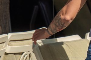 Фото татуировки на руке: акварельная татуировка с изображением цветка, выполненная в нежных пастельных тонах с добавлением серых элементов.