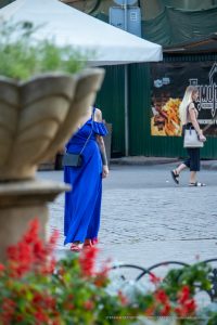 Фотография девушки в синем платье, демонстрирующая татуировки на руке, включая изображение птицы и цветочные узоры.