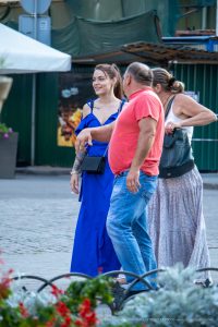 Фотография девушки в синем платье, демонстрирующая татуировки на руке, включая изображение птицы и цветочные узоры.