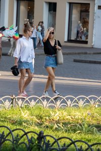 Фото двух молодых девушек, идущих по улице. На руках у одной из них видны татуировки, предположительно, в стиле минимализм.