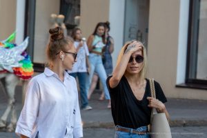 Фото молодой девушки с татуировкой на руке, смотрящей в сторону. Черно-белое изображение, акцент на татуировке и выражении лица.