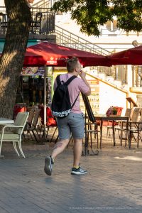 Фото тату на ноге у молодого человека, идущего по улице. Вид сзади, татуировка в стиле традиционной японской гравюры.