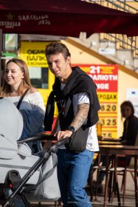 Фото тату на руке мужчины, гуляющего с коляской. Рука покрыта детализированным рисунком татуировки в стиле реализм.