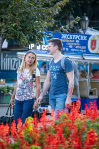 Фотография мужчины с уличной татуировкой на руке и женщины, идущих по улице. Татуировка выполнена в ярком и динамичном стиле.