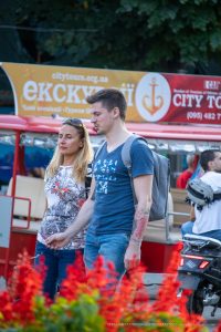 Фотография мужчины с уличной татуировкой на руке, сделанной в ярком и динамичном стиле. Татуировка выделяется на фоне городской среды.