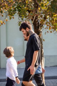 Фото тату на руке мужчины. Виден фрагмент рисунка, вероятно, геометрический узор или абстракция. Изображение сделано на улице, в повседневной обстановке.