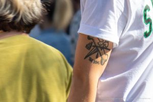 Фото тату на предплечье: стилизованное изображение кости, кинжала и капли, выполненное в черном цвете. Лаконичный рисунок татуировки.