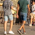 Фотография двух мужчин на улице, у одного из которых видна татуировка на ноге. Современный стиль, уличная татуировка.