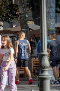 Фото тату слона на спине мужчины, выполненное в черно-белом стиле. Мужчина стоит на улице.