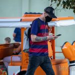 Фото тату розы и черепа на руке мужчины в футболке. Черно-белый рисунок татуировки в стиле реализм.
