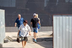 Фотография уличной моды: люди с татуировками на руках и ногах, идущие по городской улице. Снимок передает атмосферу свободы и самовыражения.