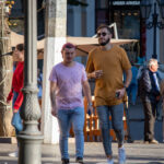 Фото мужчины с татуировкой на руке, одетого в желтую футболку и кепку. Рисунок татуировки выполнен в черных тонах и имеет сложную структуру.