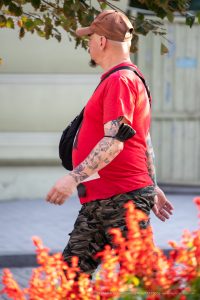 Фото тату на руке мужчины: детализированные рисунки в стиле олдскул и традиционные мотивы, покрывающие предплечье и плечо, на фоне цветущих растений.