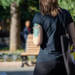 Фото тату на плече женщины: изображение птицы в ярких акварельных тонах, с плавными переходами цветов и детальной проработкой перьев.
