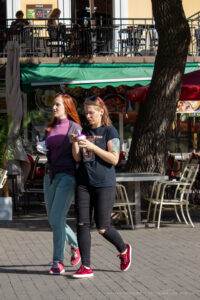 Фото тату: девушка с акварельными татуировками на руках, идущая по улице с подругой.