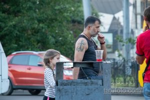 Фото тату на плече мужчины: якорь и православный крест, выполненные в черном цвете. Детализированный рисунок татуировки символизирует веру и надежду.