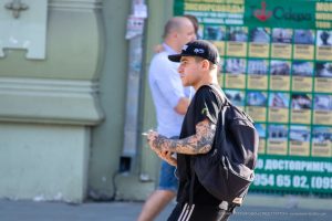 Фотография мужчины с татуировкой на руке, изображающей череп, увитый цветами. Черно-серый рисунок татуировки на предплечье.