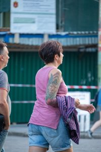 Фото тату павлина на плече женщины. Цветная татуировка с детально проработанными перьями и яркой цветовой гаммой. Идея для тату в стиле реализм.