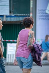 Фото тату павлина на плече женщины. Цветная татуировка с детально проработанными перьями и яркой цветовой гаммой. Идея для тату в стиле реализм.