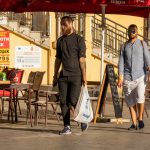 Фото мужчины с татуировкой на руке, изображающей детализированный рисунок, виднеющийся из-под рукава рубашки.