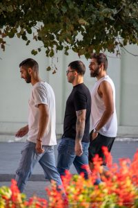 Фотография мужчины с татуировкой на руке, идущего по улице в повседневной одежде.