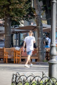 Фото мужчины с татуировками на руках и ногах, идущего по улице: детализированные рисунки в различных стилях.