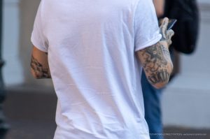 Фото тату: чёрно-серая татуировка на руке мужчины, выполненная в реалистичном стиле с изображением различных элементов, таких как часы и цветы.