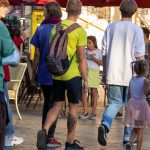 Фото татуировки дракона на голени мужчины, идущего по улице. Виден фрагмент тату, сочетающийся с повседневным стилем одежды.