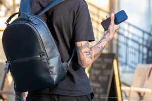 Фото тату на руке мужчины, держащего телефон. Детализированные рисунки, уличный стиль, современная татуировка.