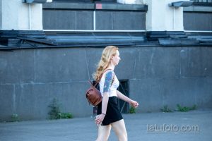 Фото тату на руке: красочный дракон в традиционном стиле, обвивающий руку девушки. Использованы яркие цвета и четкие линии.