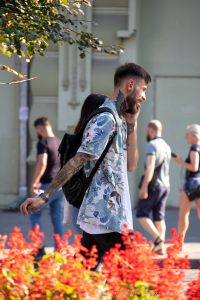 Фото тату: мужчина с ярким рукавом татуировки на руке, изображающим цветы и узоры. Детализированный рисунок татуировки.
