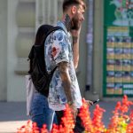 Фото тату: мужчина с татуировками на руках и шее, изображающими цветы и узоры. Детализированный рисунок татуировки.