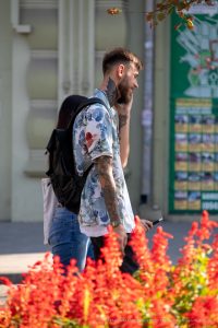 Фото тату: мужчина с татуировками на руках и шее, изображающими цветы и узоры. Детализированный рисунок татуировки.